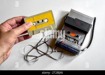 Mano che tiene una cassetta che si è aggrovigliata nel lettore Foto Stock