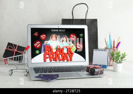 Computer portatile con pubblicità in vendita del Black Friday, carte di credito e confezioni regalo su un tavolo bianco Foto Stock