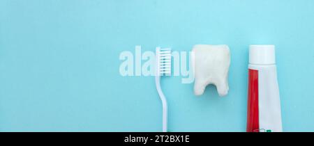 Primo piano di uno spazzolino da denti e di un dentifricio con un modello bianco a denti molari su sfondo blu sfocato. Significa prendersi cura della cavità orale Foto Stock