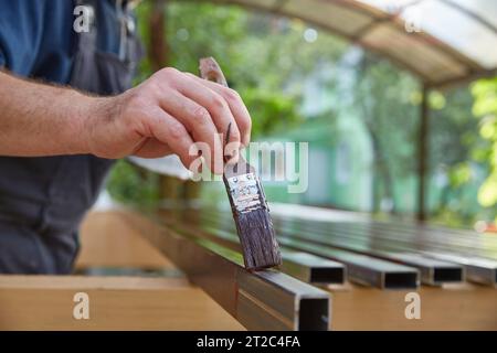 La mano di un uomo dipinge tubi quadrati di metallo con un primer sul metallo. Copia spazio Foto Stock