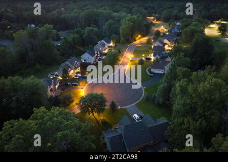 Case da sogno americane di notte in una strada rurale senza strade chiuse nei sobborghi degli Stati Uniti. Vista dall'alto delle case residenziali illuminate in un'area soggiorno di Foto Stock