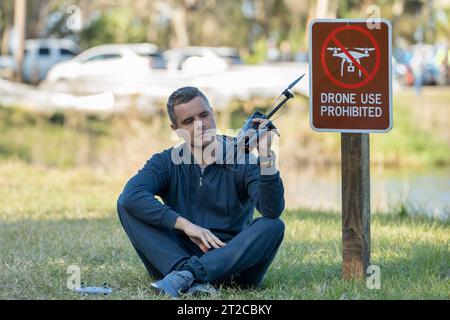 L'uomo volerà il suo quadricottero in nessuna zona di droni. L'operatore utilizza illegalmente il proprio UAS nel parco statale vicino al segnale di restrizione Foto Stock