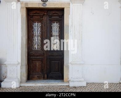 Vecchia porta in legno su una facciata dipinta di bianco Foto Stock
