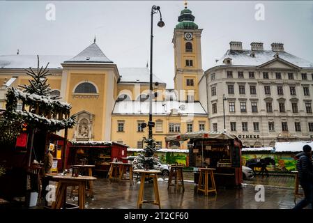 Monastero di Schottenstift a Vienna, Austria e piazza del mercato di Natale Freyung sulla neve con il priorato di Schublandkastenhas. Foto Stock