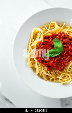 Piatto di pasta di spaghetti italiani di primo piano su un tavolo da cucina in marmo bianco brillante Foto Stock