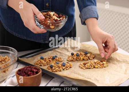 Preparare barrette di muesli. Donna con le noci a tavola in cucina, primo piano Foto Stock