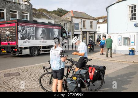 Uomo e donna con biciclette da turismo che indossano bavaglini Tour of Britain a Padstow, Cornovaglia, 2023 settembre, Inghilterra Foto Stock