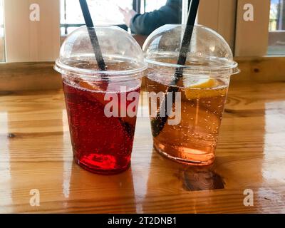 Due bicchieri di plastica, rosso e giallo, rinfrescante, freddo, gustoso e dolce, lampone, fragola, ciliegia, arancia, pesca, limone, limonata naturale con cannuccia A. Foto Stock