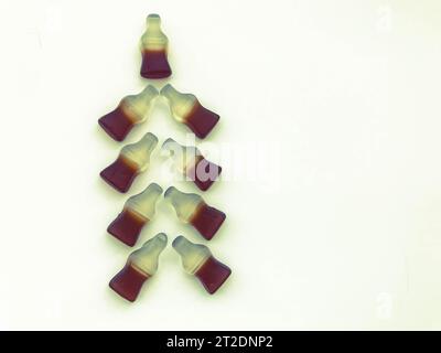 Albero di Natale realizzato con bottiglie gommose con limonata su sfondo bianco opaco. Albero di Natale insolito fatto di dolci. Un regalo di Natale. Foto Stock