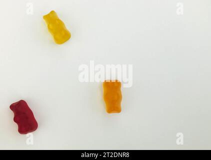 orsi gommosi su sfondo bianco opaco. orso rosso, giallo e arancione giacciono sul tavolo. caramelle di nostra produzione. dolci per decorare torte e. Foto Stock