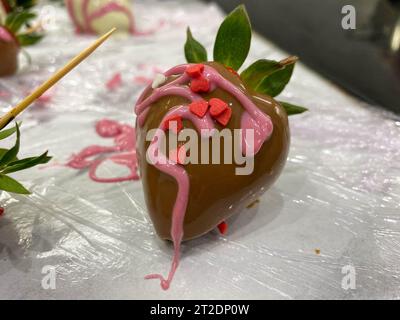 Fragole ricoperte di cioccolato in una confezione regalo con coperchio trasparente e nastro grigio e busta con cera sigillante. Foto Stock