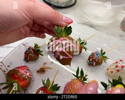 Fragole fresche immerse in cioccolato fondente su sfondo di legno blu. Foto Stock