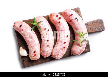 Salsicce crude con rosmarino e spezie su tagliere di legno isolate su fondo bianco. Foto Stock