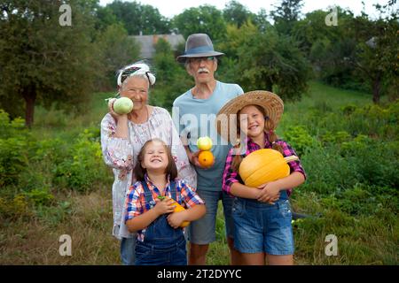Buona coppia nonna e nonno con nipoti che tengono il raccolto di verdure. Contadini cibo orgaiico. Felice vita familiare Foto Stock