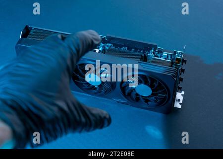 la mano di un tecnico informatico contiene una potente e moderna scheda per videogiochi per un computer con tre fan. Il concetto di hardware per PC. Video car di gioco Foto Stock