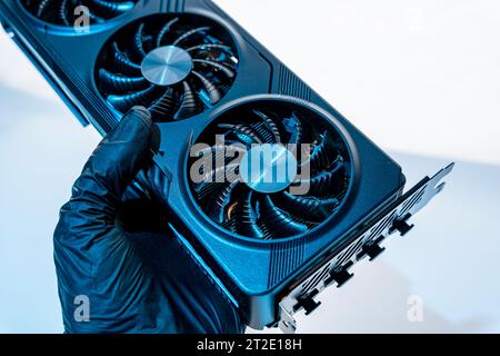 la mano di un tecnico informatico contiene una potente e moderna scheda per videogiochi per un computer con tre fan. Il concetto di hardware per PC. Video car di gioco Foto Stock