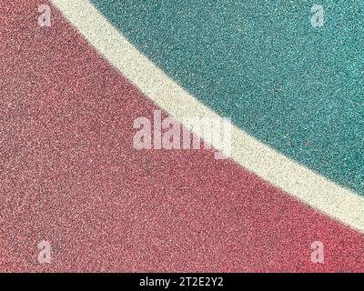 rivestimento antiscivolo per un campo da basket sportivo. texture rossa con schizzi bianco-verde. pietre di colori diversi. sfondo di piccole pietre. Foto Stock