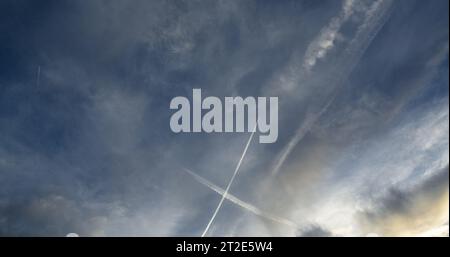 Gioco ipnotico di luce e ombra creato dalle piste di condensazione di un aereo di linea e dalle nuvole ad alta quota. Foto Stock