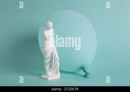 Una Venere di Milo davanti a un palloncino turchese dello stesso colore dello sfondo. Monocromatico e sfumature di colore. Contrasto tra una scultura classica Foto Stock