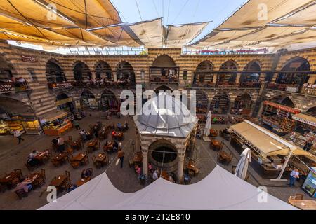 DIYARBAKIR, TURCHIA, 5 OTTOBRE 2023: Veduta di Hasanpasa Khan, edificio storico medievale dove la gente fa colazione e piccoli negozi, il centro Foto Stock