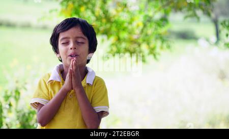 Bambino che prega la mattina. Piccolo ragazzo asiatico che prega, mani piegate in concetto di preghiera per fede, spiritualità e religione. bambino bambino bambino w Foto Stock