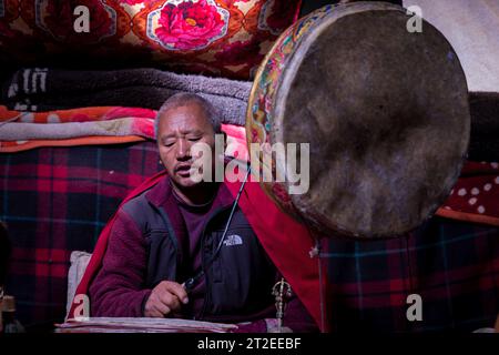 Il monaco buddista esegue la puja in una tenda nomade, Ladakh, India Foto Stock