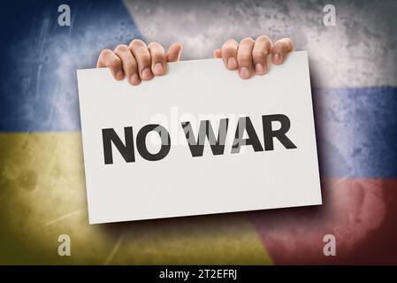 Concetto di protesta contro la guerra tra Russia e Ucraina con le mani che reggono un segno con testo e bandiere dietro. Foto Stock