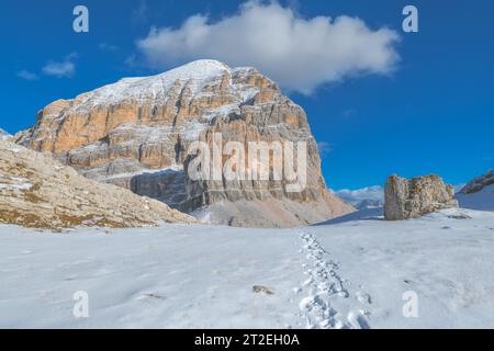 Un sentiero nella neve fresca conduce alla base del monte Tofana di Rozes nelle Dolomiti d'Ampezzo. Massiccia montagna con facce stratificate. Foto Stock