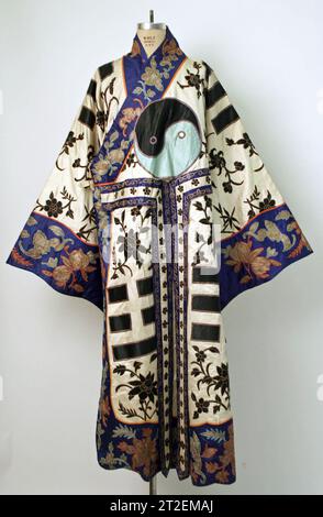 Vestaglia teatrale con otto trigrammi in Cina alla fine del XIX secolo, questa veste presenta simboli usati nella divinazione taoista, tra cui una rotonda in bianco e nero (taiji) sulla parte anteriore e posteriore e otto serie di trigrammi neri (bagua). Un indumento teatrale come questo era generalmente indossato per interpretare uno stratega con potere magico. È stato utilizzato, ad esempio, da un attore che interpreta Zhuge Liang (181-234) dalla commedia Yangping Pass.in vista durante la Rotation 1 della mostra dal 25 giugno 2016 al 13 gennaio 2017. Foto Stock