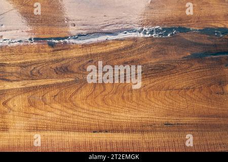 La consistenza del vecchio legno con una crepa e resina epossidica trasparente. Splendido sfondo moderno in legno con resina. Foto di alta qualità Foto Stock