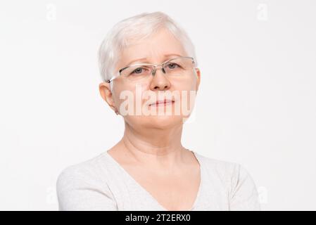 Ritratto di una donna anziana di mezza età sana che indossa occhiali da vista con sfondo bianco isolato ripresa in studio Foto Stock