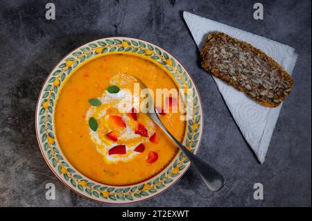 Un caldo pasto autunnale con zuppa di zucca e una fetta di pane scuro. Foto Stock