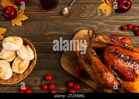 tacchino del ringraziamento e panini su tavola di legno con fogliame dorato e pomodori ciliegini rossi con mele Foto Stock