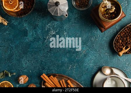 caffè del giorno del ringraziamento, recipiente per geyser e macinacaffè manuale vicino a bastoncini di cannella su una superficie rustica blu Foto Stock