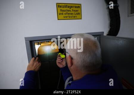 Bad Brahmstedt, Germania. 18 ottobre 2023. Un dipendente di un'azienda di gasolio e gasolio per riscaldamento controlla il livello nei serbatoi durante la consegna di olio per riscaldamento a un cliente in una casa a conduzione familiare. Credito: Christian Charisius/dpa/Alamy Live News Foto Stock