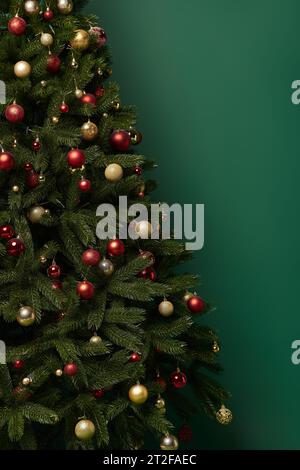 Albero di Natale decorato con bellissimi bauble su sfondo verde scuro, concetto invernale Foto Stock