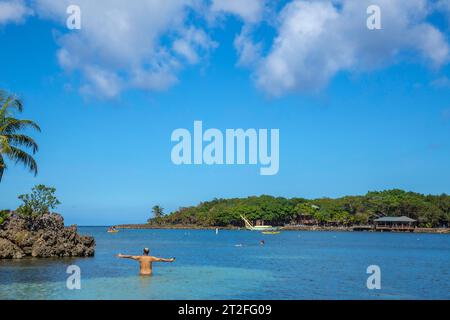 Un giovane che entra nel Mar dei Caraibi a West End Beach sull'isola di Roatan. Honduras Foto Stock