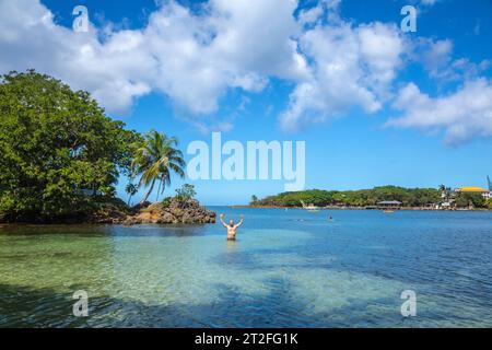 Un giovane che entra nel Mar dei Caraibi a West End Beach sull'isola di Roatan. Honduras Foto Stock