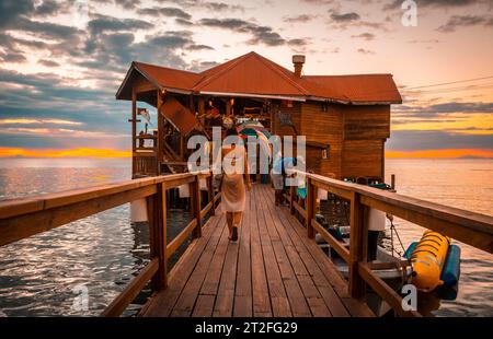 Roatan, Honduras Â», gennaio 2020: Una giovane donna che cammina al tramonto nell'edificio in legno del West End sull'isola di Roatan Foto Stock