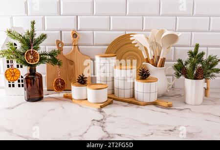 Splendido sfondo della cucina di Capodanno con un set di utensili da cucina e vasetti per conservare il cibo, decorati con rami natalizi con decorazioni naturali Foto Stock