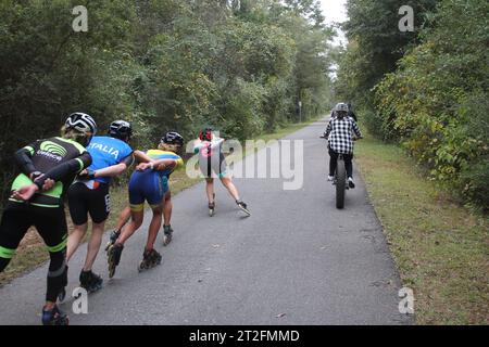 Pattinatori in linea che superano una famiglia di ciclisti (attività di gruppo su un percorso) Foto Stock