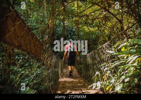 Un giovane che cammina lungo uno splendido ponte di legno nel Parco Nazionale del Cerro Azul Meambar (Panacam) sul lago Yojoa. Honduras Foto Stock