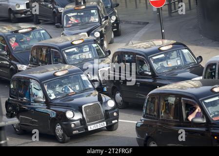 Traffico intenso di iconici taxi neri di Londra in una strada trafficata nel centro di Londra, che illustra il trasporto urbano del Regno Unito e la congestione Foto Stock