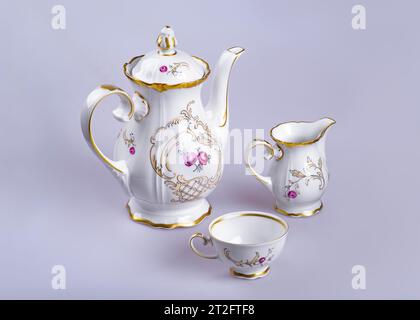 Un vecchio tè tedesco in terracotta (caffè) con una teiera, una tazza di latte e una tazza su sfondo grigio-grigio Foto Stock