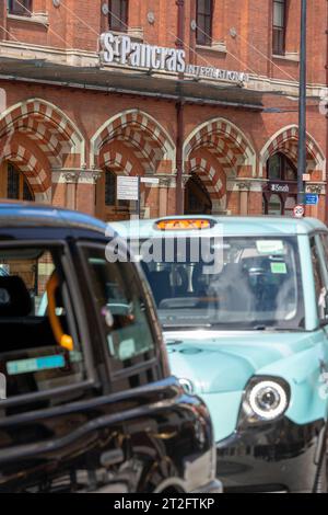 Taxi neri fuori da St Pancras International a Londra, con l'iconica facciata in mattoni rossi della stazione e la segnaletica. Solo per uso editoriale Foto Stock
