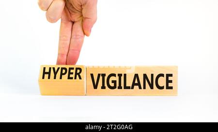 Simbolo di vigilanza o ipervigilanza. Parole concettuali Vigilance Hypervigilance su blocchi di legno. Splendido sfondo bianco. Mano psicologa. Psicologia Foto Stock
