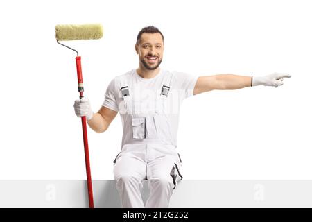 Verniciatore con rullo di vernice posizionato su un pannello vuoto e rivolto verso il lato isolato su sfondo bianco Foto Stock