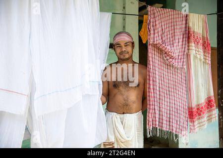 Monaco indù in abiti tradizionali in piedi asciugando i vestiti presso il monastero indù di Uttar Kamalabari, isola di Majuli, Assam, India Foto Stock