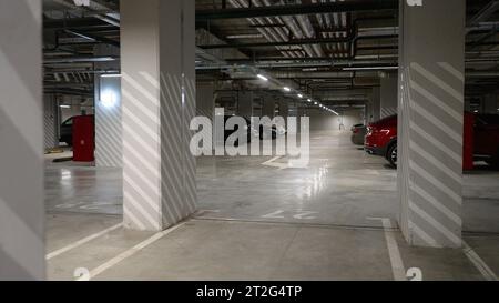 Parcheggio sotterraneo sotto un moderno appartamento in un complesso residenziale, auto parcheggiate, nessuno, molto spazio parcheggio gratuito. Parcheggio sotto una zona residenziale Foto Stock