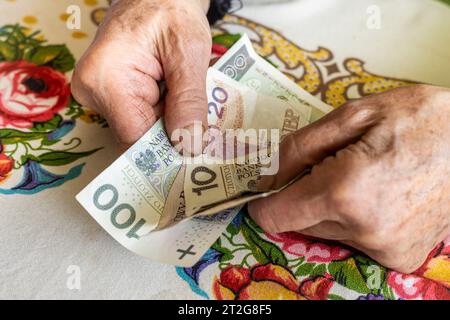 La vecchia pensionessa polacca stringe il denaro nelle sue mani, piccola quantità, concetto, difficile situazione finanziaria degli anziani in Polonia, aumento delle tasse Foto Stock